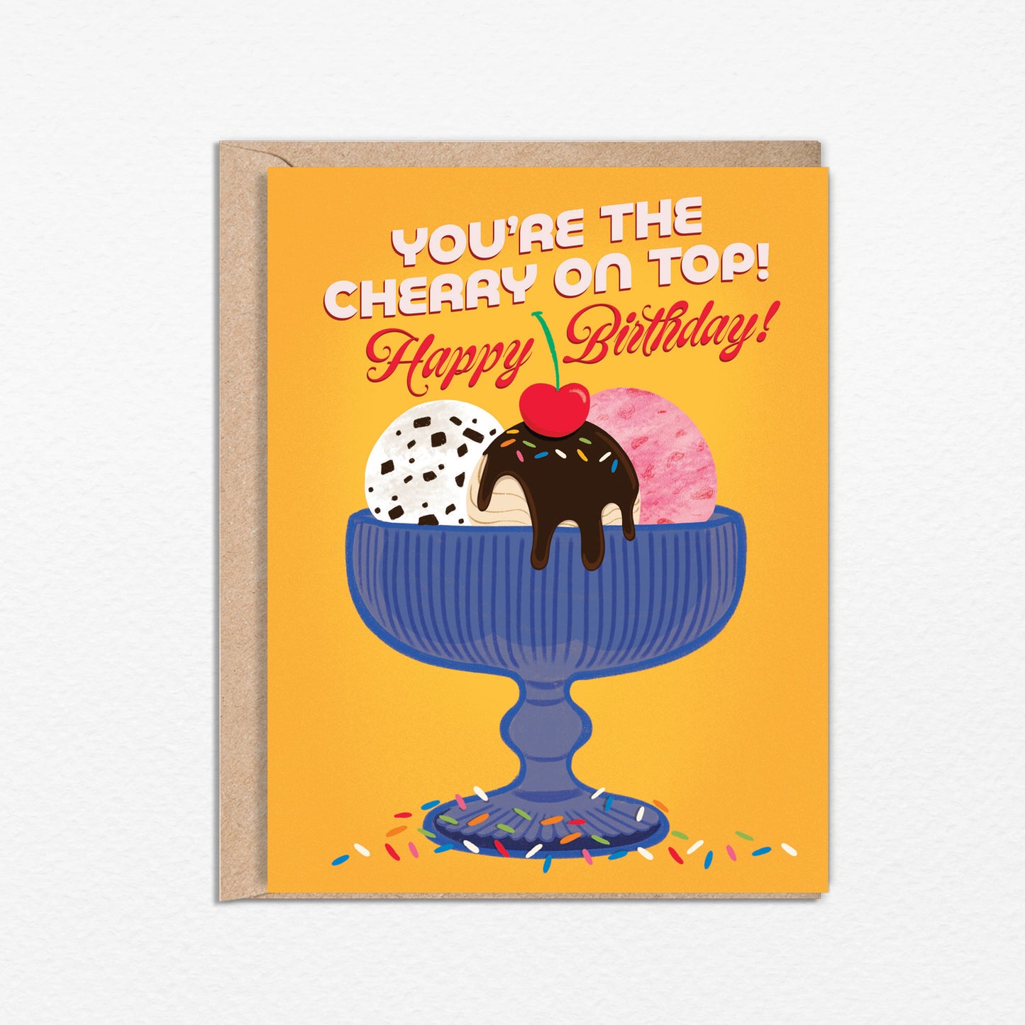 A2 size birthday card featuring blue antique glass ice cream bowl with chocolate chip, strawberry, and fudge salted caramel ice cream illustration on a warm yellow background. “You’re the cherry on top! Happy Birthday” text on the front in white and red. The message inside reads “Happy Birthday!”,. Envelope included.