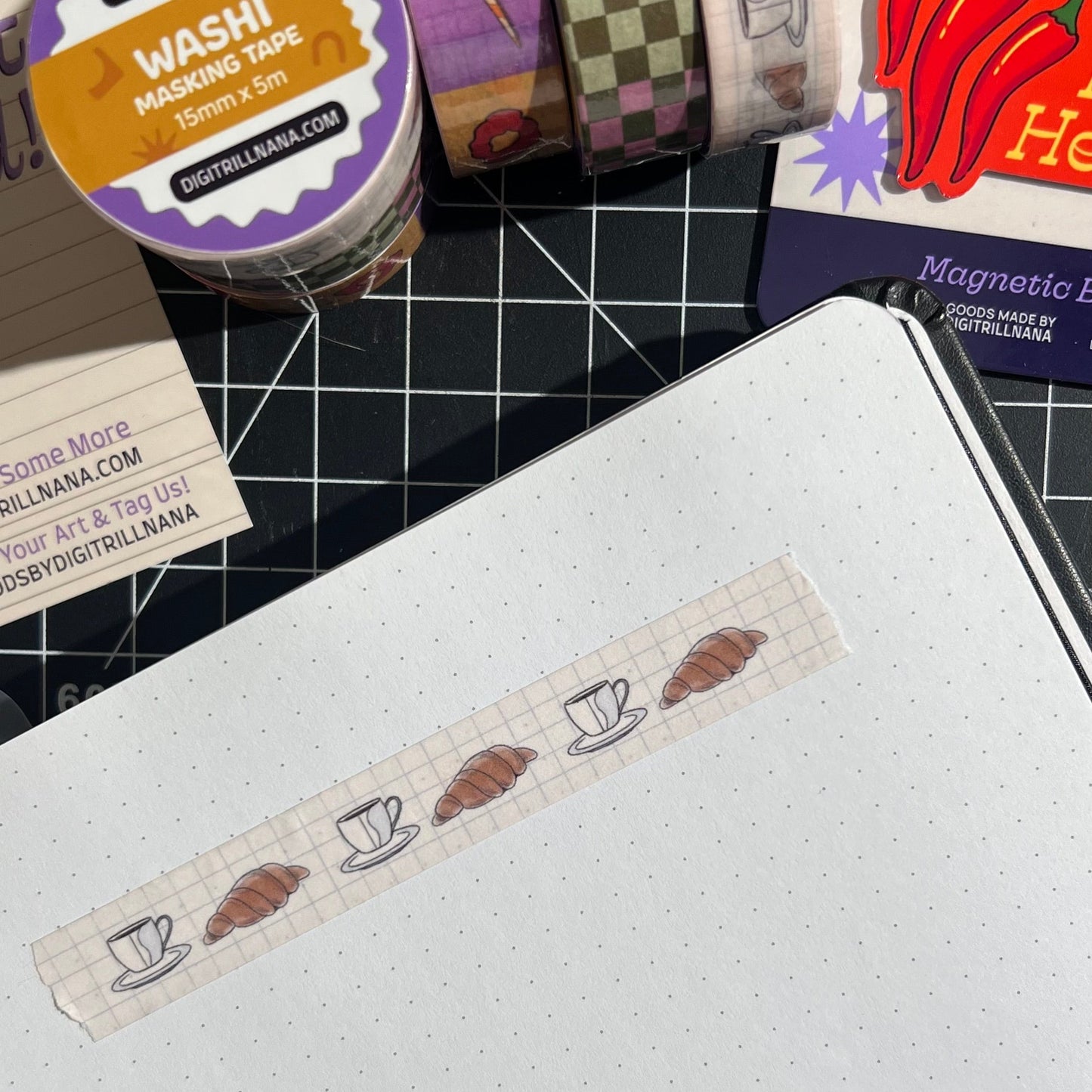 15mm sem-transparent washi tape roll featuring a illustrated coffee cup and saucer and croissant on a light blue grid background. re-adjustable and removable. Perfect for your planner, junk journal, and scrapbook.
