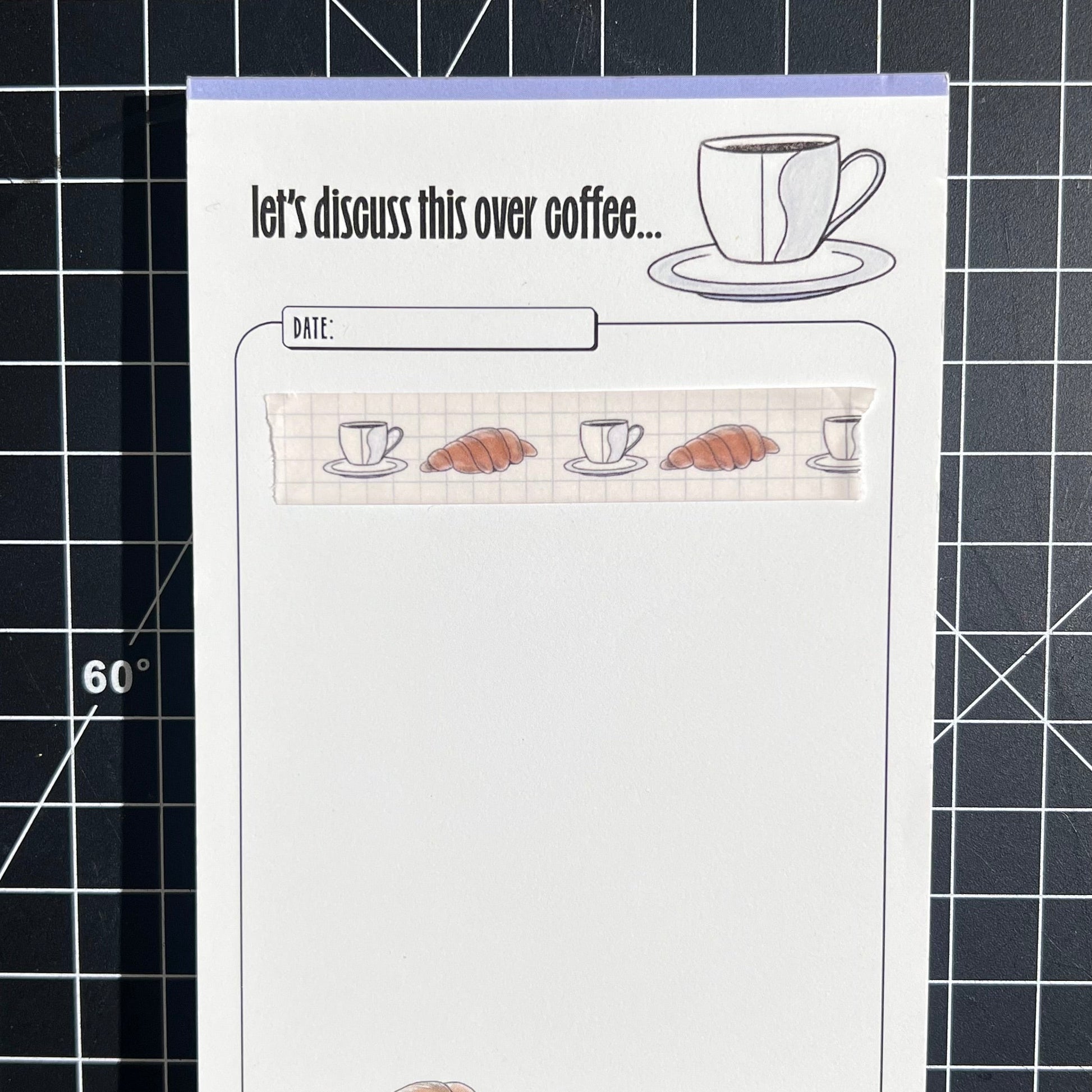 15mm sem-transparent washi tape roll featuring a illustrated coffee cup and saucer and croissant on a light blue grid background. re-adjustable and removable. Perfect for your planner, junk journal, and scrapbook.