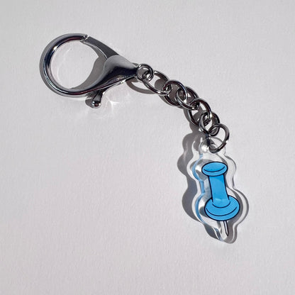 1” double-sided clear acrylic push pin keychain in textured baby blue with silver U-shaped hook clasp. Aesthetic bag charm for tote bags, backpacks, and crossbody bags. Perfect gift for stationery lovers. 