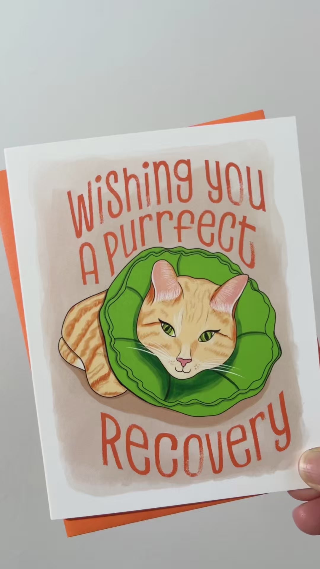 Purrfect Recovery greeting card box set. Card illustration of a tabby cat laying down wearing a green soft cat recovery cone collar. The text in orange reads, "Wishing you a purrfect recovery". Blank inside. Envelope included.