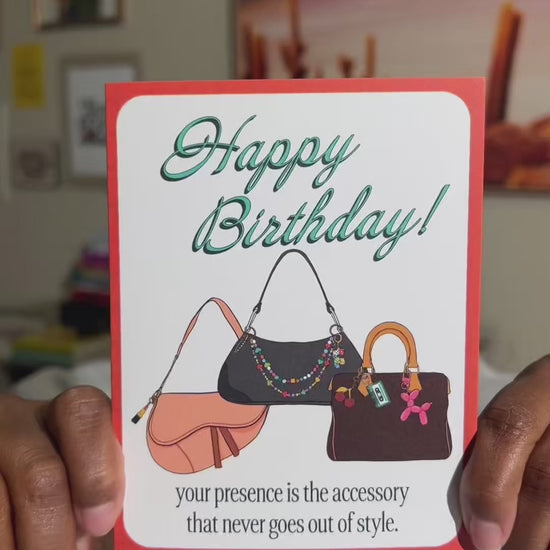 4.25 x 5.5” A2 illustration of dior saddle bag, and two shoulder bags with colorful bag charms. “Happy Birthday!" text in turquoise and “your presence is the accessory that never goes out of style.” at the bottom. Blank inside. Envelope included. 