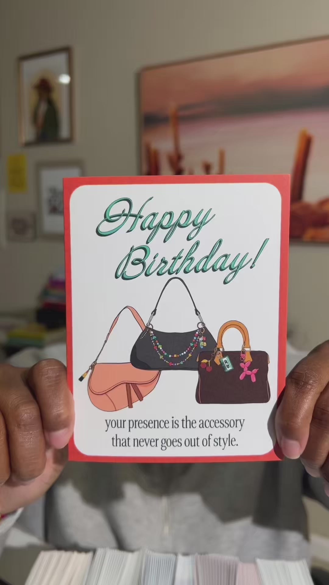 4.25 x 5.5” A2 illustration of dior saddle bag, and two shoulder bags with colorful bag charms. “Happy Birthday!" text in turquoise and “your presence is the accessory that never goes out of style.” at the bottom. Blank inside. Envelope included. 