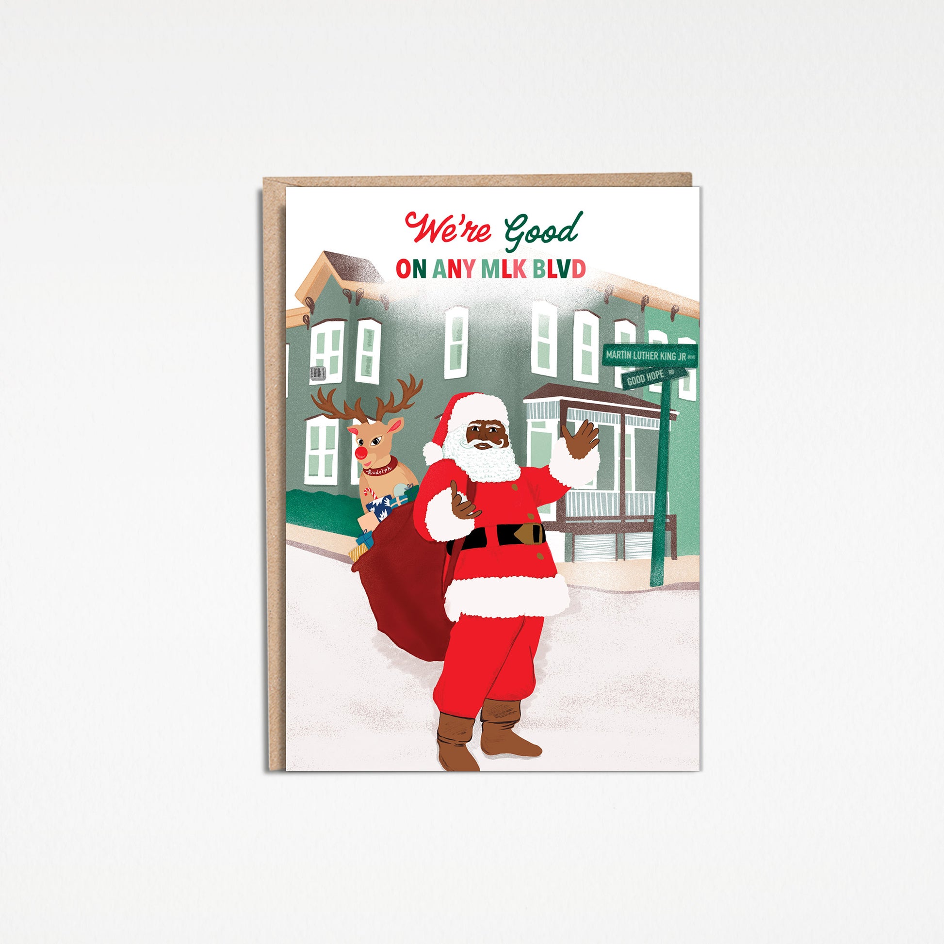 High quality 5x7 inch Christmas greeting card illustration titled Santa’s Hood illustrates Black Santa Claus standing in the street on the corner of Martin Luther King Jr Blvd and Good Hope Road in Washington DC. Santa has a red sack on his shoulder filled with presents and Rudolph the rednosed reindeer behind him. A green colored house sits in the background. The sky has snow falling with the words “We’re Good On Any MLK Blvd” in red and green.